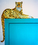 Free standing painting of a perched leopard, painted on wood.